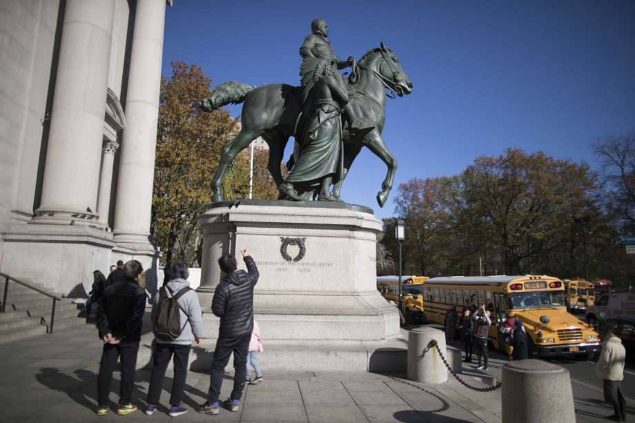In this Nov. 17, 2017 file photo, visitors to the American Museum of Natural History in New York look at a statue of Theodore Roosevelt, flanked by a Native American man and African American man. The statue will be coming down after the museum's proposal to remove it was approved by the city Photo: Mary Altaffer, AP / Copyright 2017 The Associated Press. All rights reserved.